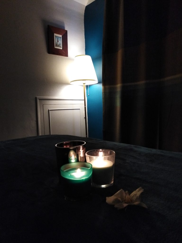 Bout de table de soins sur lequel sont posées des bougies allumées ainsi qu'une fleur d'orchidée.
la pièce est plongée dans une atmosphère extrêmement tamisée, propice à la relaxation.