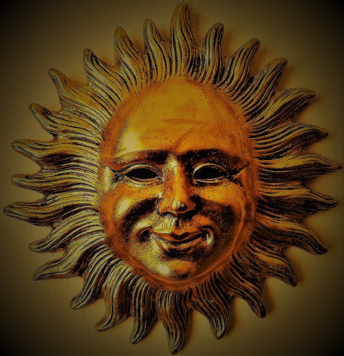 Soleil vénitien doré figurant un visage humain souriant et bienveillant.